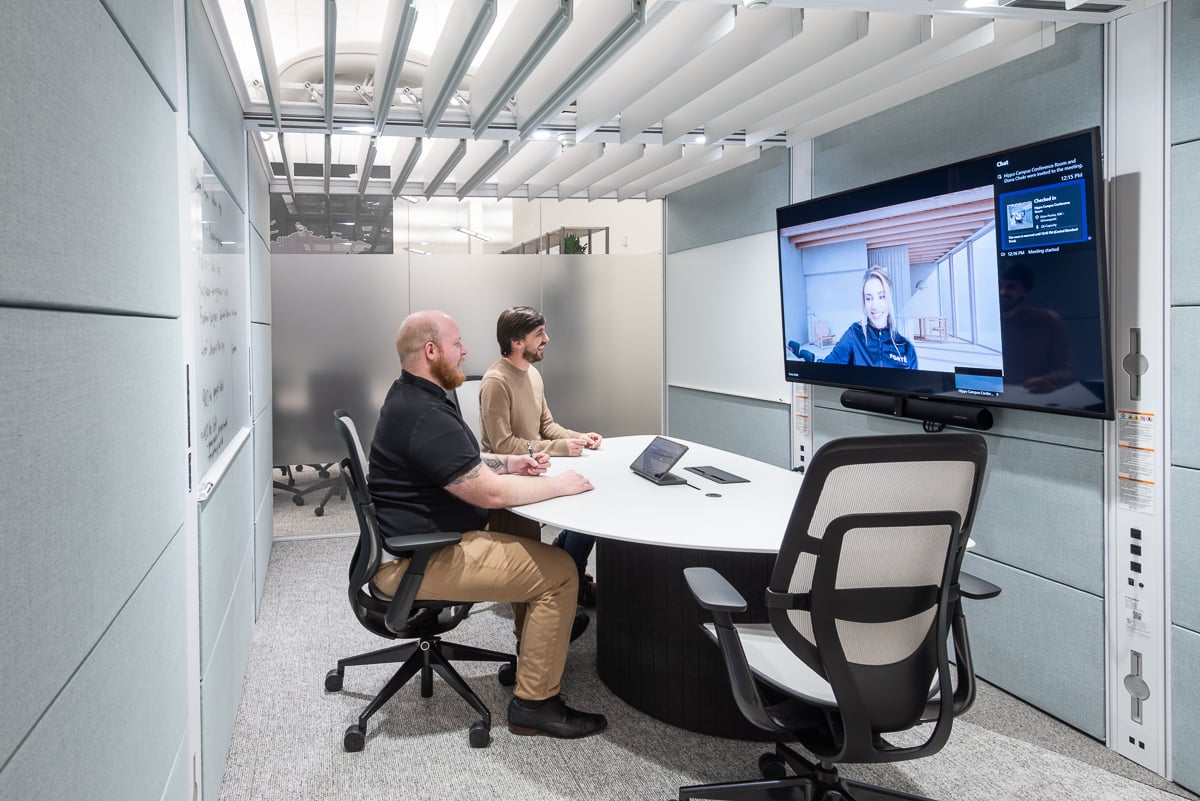 Two employees participating in a video meeting in a private conference room