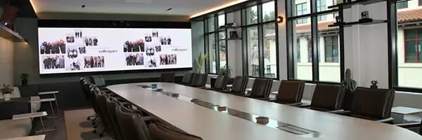 Large executive boardroom with chairs arranged facing each other with a large monitor at the head of the room.