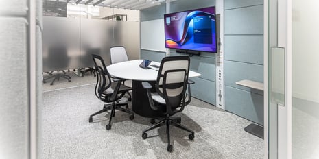 Small conference room with three chairs around a semi-circle table and monitor at the head. 