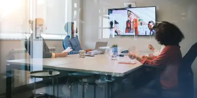three people in a conference room behind glass looking at display in a meeting