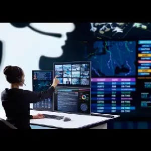 Woman on a headset interacting with a large touch panel at a desk.