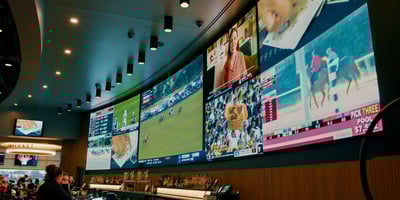 Multi-purpose video LED wall displaying sports and programming above a bar full of people.