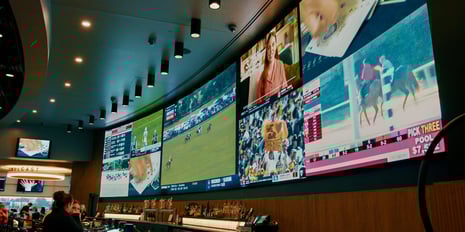 Multi-purpose video LED wall displaying sports and programming above a bar full of people.