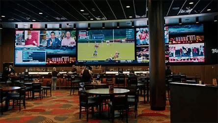 People sitting in a casino dining area watching tv on a large multi-purpose LED display wall.
