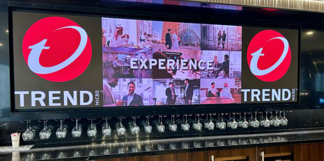 Large led wall displaying Trend Micro logo above a bar with wine glassed hanging below.