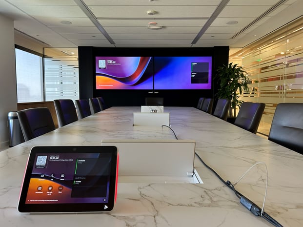 A sleek boardroom with a marble conference table and large digital display screens.