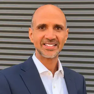headshot of Taj Ghere looking at the camera in a suit