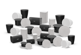 A collection of assorted Bose speakers in black and white, featuring round, rectangular, and cylindrical designs, arranged together on a dark background.