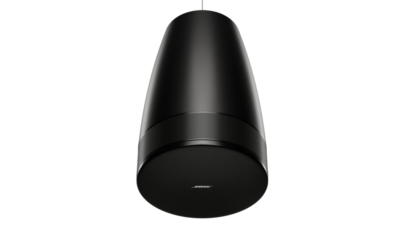 A sleek black cylindrical pendant speaker hangs from the ceiling against a dark background, with a smooth matte finish and subtle perforated grille around its lower half.