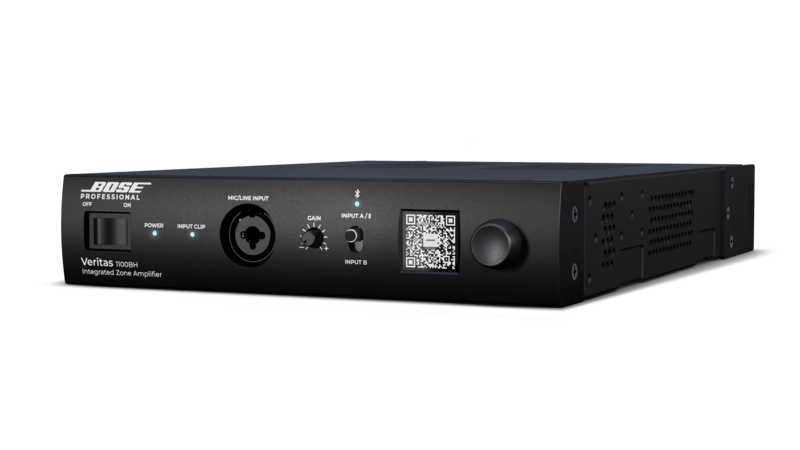 Angled front view of a black Bose Professional Veritas 1100BH integrated zone amplifier featuring a power switch, microphone input, gain and input selectors, a QR code display, and a large control knob on a sleek rack-mount chassis against a dark background.